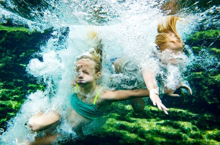 Two girls leaping into Jacob's Well in the Texas Hill Country.