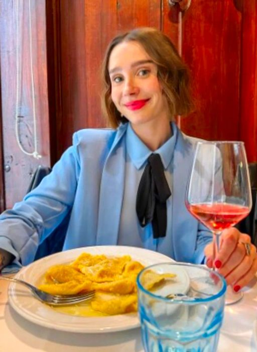 Amanda Montell, author and podcast host, enjoying dinner with a glass of wine in hand.