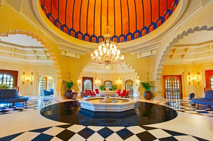 The lobby of Oberoi Udaivilas, adorned in blue, white, and gold, beautifully reflects the region's vernacular architecture, featuring domes, arches, and elements of water.