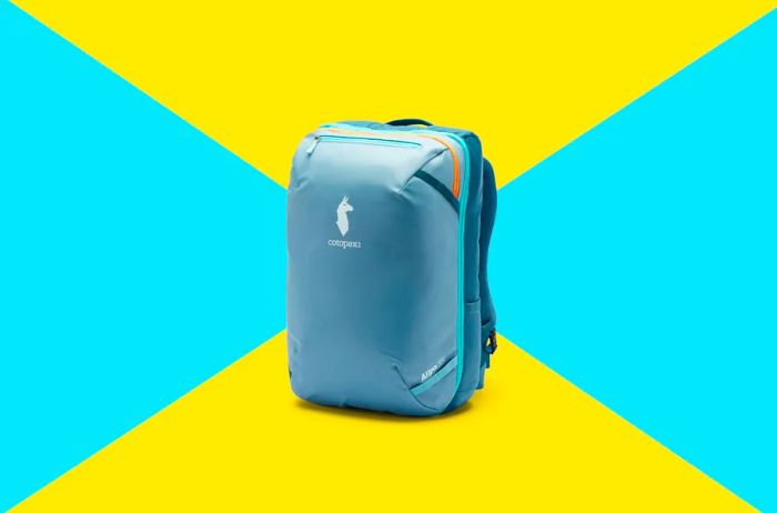 A teal travel backpack featuring the Cotopaxi logo with a llama head in profile