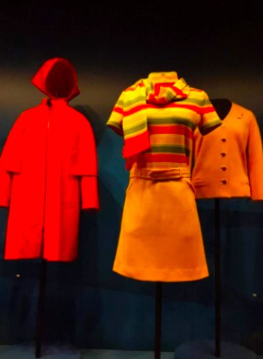 1960s flight attendant uniforms for TWA include a red hooded cape, a yellow cardigan, and a striped T-shirt paired with a yellow miniskirt.