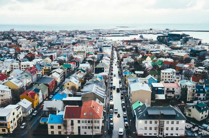 Aerial view of Reykjavík showcasing a mix of vibrant and neutral-colored buildings with the sea in the background.