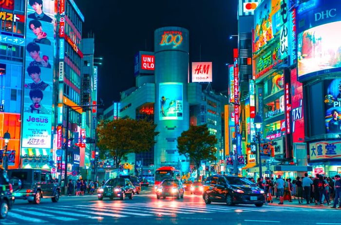 A city street illuminated at night, showcasing vibrant neon signs on buildings