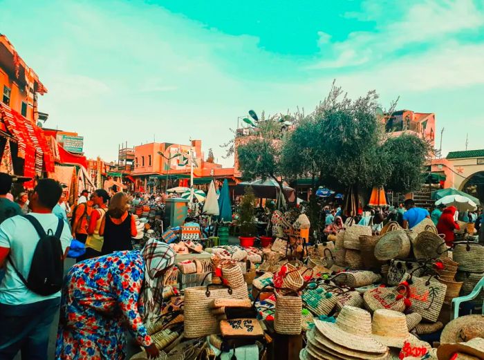 A vibrant market scene in Marrakech featuring woven baskets and hats in the foreground