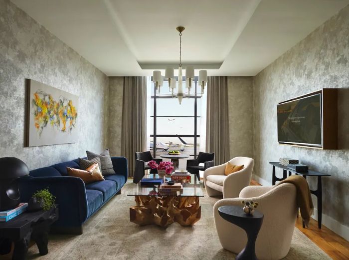 A private suite at PS Atlanta features a blue couch, two cream armchairs, and a large window overlooking the runway.