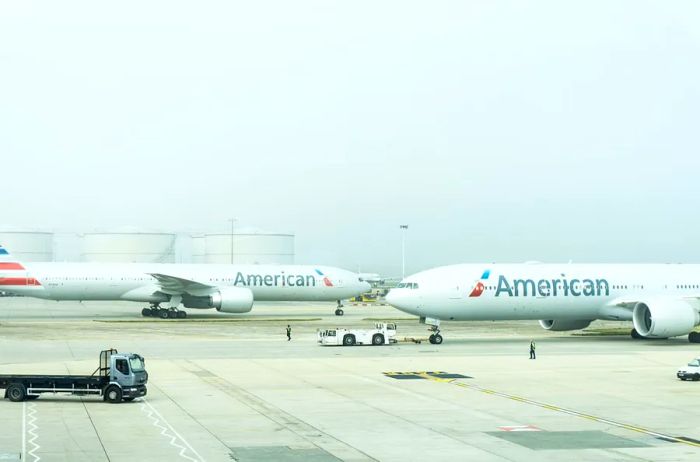 Two American Airlines aircraft taxiing at an airport shrouded in fog.