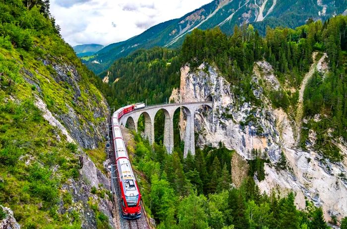 A red train winding through mountainous landscapes