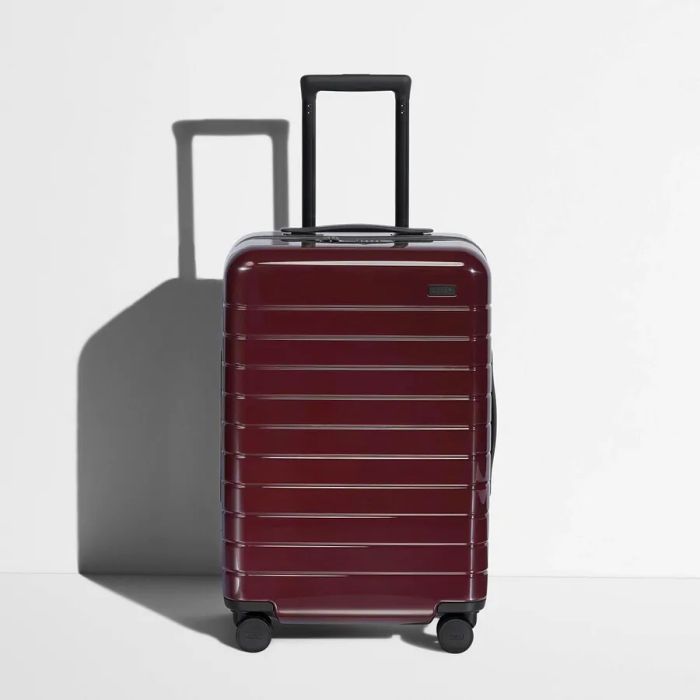 An Away suitcase with a glossy finish in a dark red hue known as Garnet