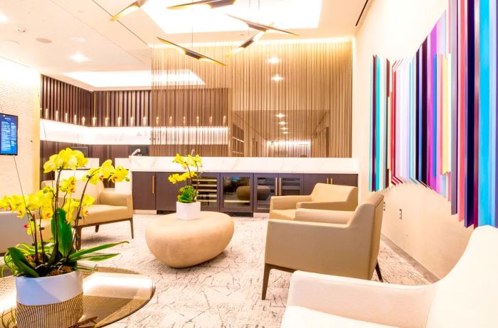 Lounge area in the new Delta One facility at LAX featuring armchairs, coffee tables adorned with yellow orchids, and contemporary artwork