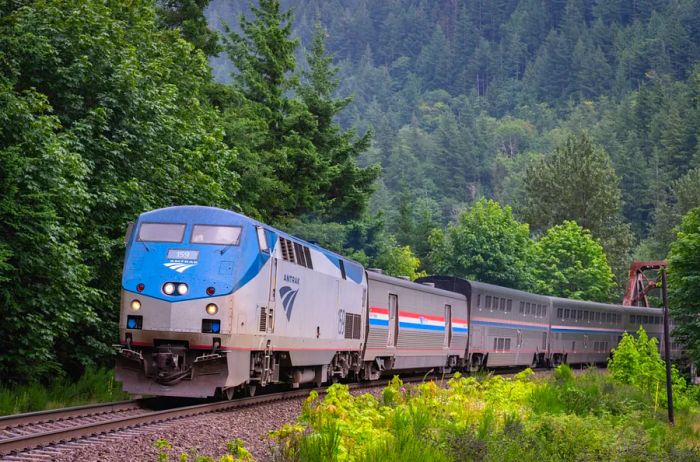 Amtrak train navigating through the breathtaking Cascades mountains surrounded by lush forest