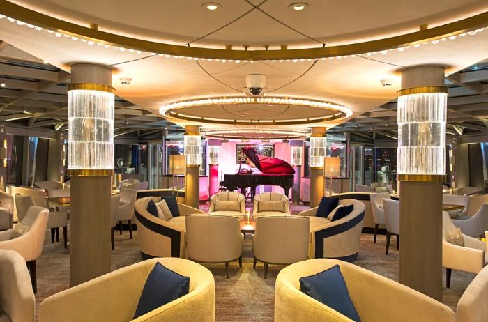 The lounge on 'Riverside DeBussy' features a central grand piano surrounded by elegant black-and-cream club chairs.