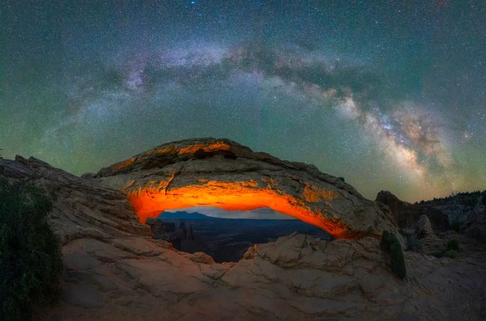 Milky Way Galaxy panorama over a lit Mesa Arch in Canyonlands National Park, Utah