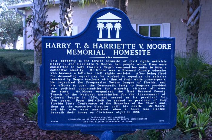 A standard historical landmark sign, presented in dark blue, detailing the history of the homesite