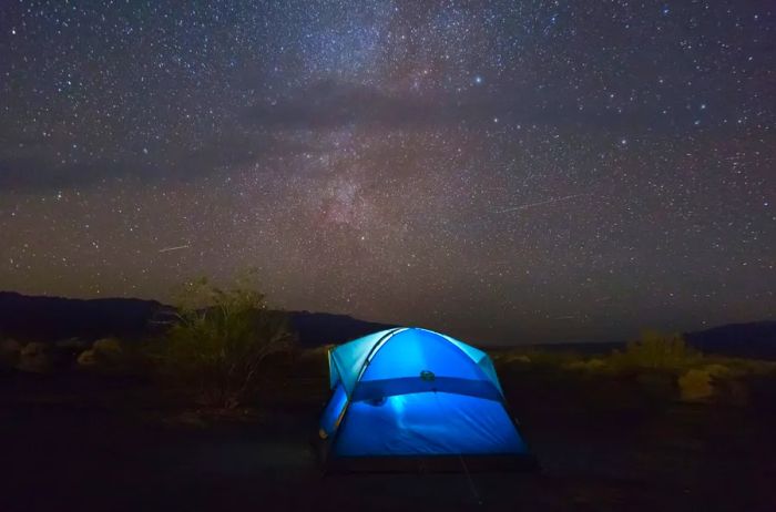 Light blue tent under the starry night sky of Death Valley National Park