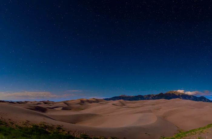 Stars shining above the sand dunes at night