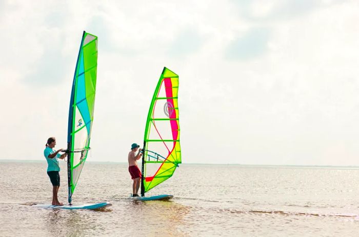 Two individuals windsurfing with vibrant sails in Corpus Christi, Texas