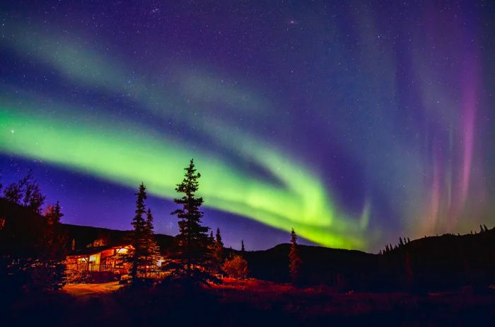 Northern lights illuminating a cabin