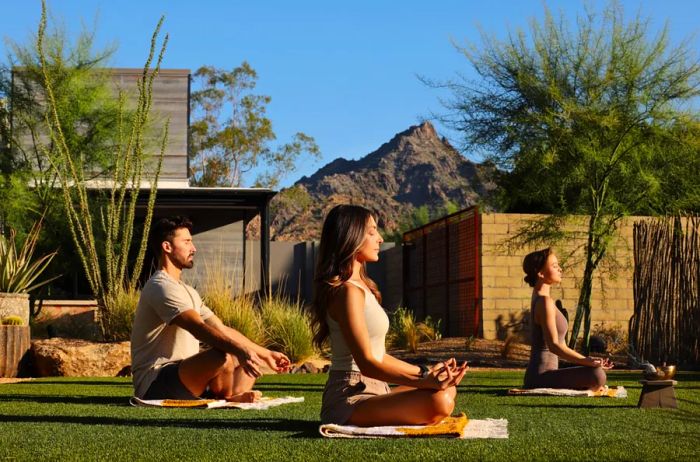 Three individuals meditating on the lawn at the Tierra Luna Spa located in Arizona Biltmore, Phoenix, Arizona