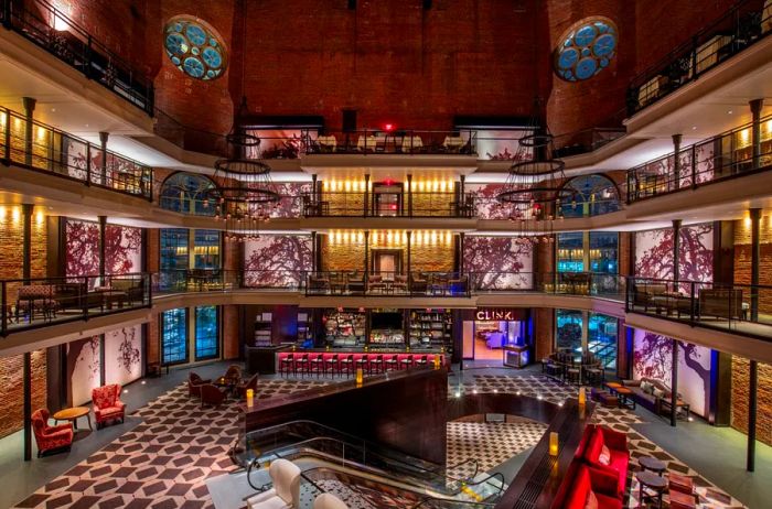 The lobby of the Liberty Hotel, a Luxury Collection Hotel, showcases elegant brown patterned carpeting and soaring hallways, with a central escalator providing access.