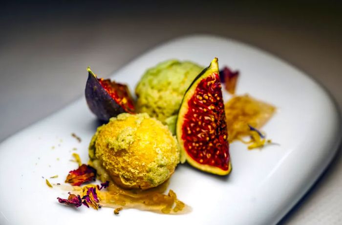 A dessert plate from the Vintage Room showcased two spheres of green and yellow desserts alongside two fig quarters and delicate shavings for garnish.