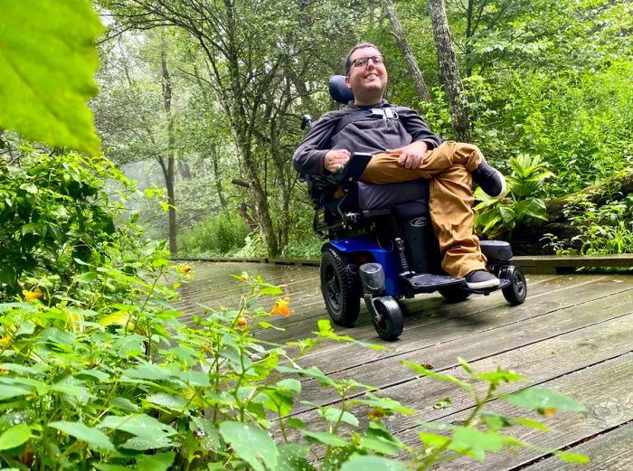 A smiling man in a powered wheelchair on a boardwalk trail in Shenandoah National Park.