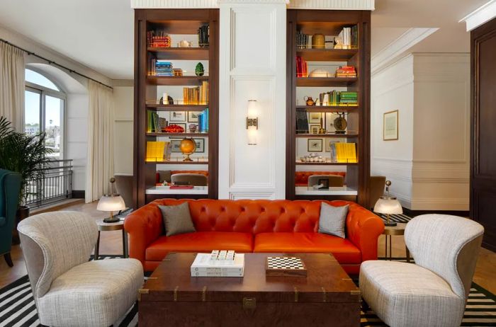 The Library at Cape Grace features a spacious tufted orange sofa alongside elegant brown bookshelves.