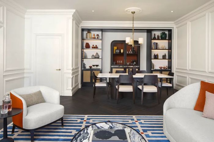 This one-bedroom suite features a lounge area adorned with black-and-white striped carpeting and a cozy nook with shelves.