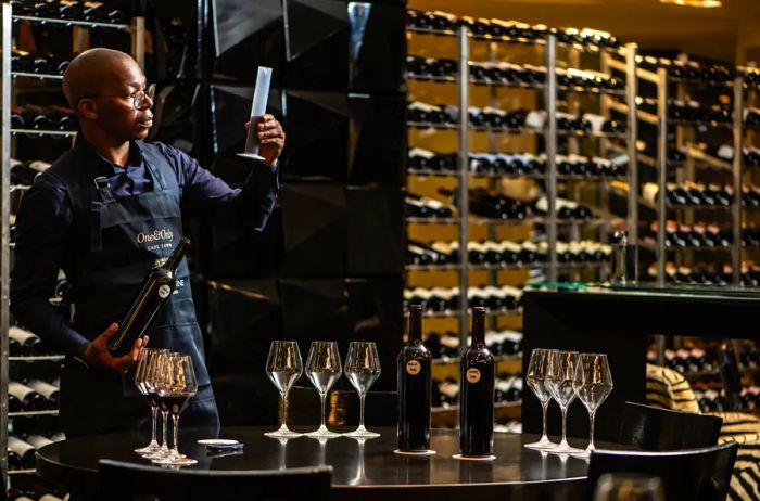 Luvo Ntezo, the head sommelier at One&Only Cape Town, inspects a graduated cylinder of wine within the wine cellar.