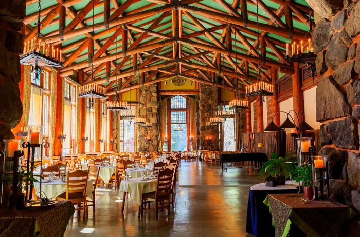 The interior of the spacious dining room at the Ahwahnee Hotel features a soaring wood-beamed ceiling and large windows.