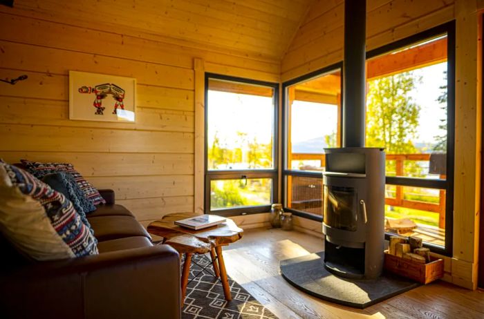 A guest room at Tordrillo Mountain Lodge features a wood-burning stove and large windows that open onto a veranda.