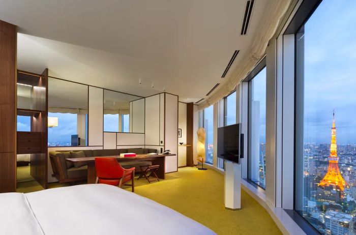 A guest room at Andaz Tokyo Toranomon Hills, showcasing a wall of windows that offers sweeping views of the city.