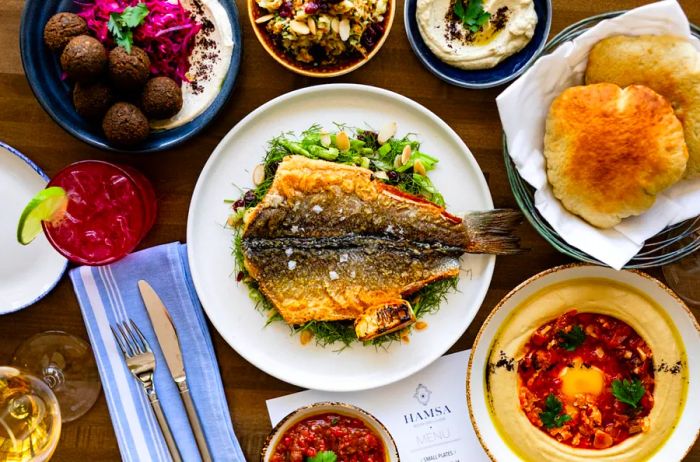 An overhead view of an assortment of dishes, including pan-fried fish, at Hamsa.