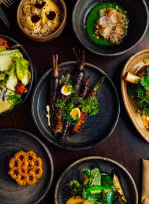 Overhead view of a selection of dishes presented in dark bowls at Jun restaurant.