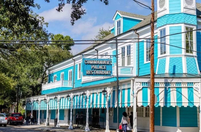 The exterior of Commander's Palace, featuring a teal building adorned with teal-and-white striped awnings.