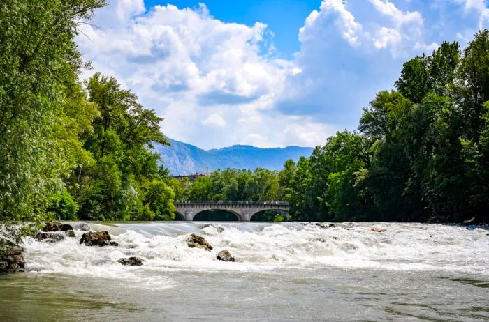 Rushing water flowing beneath a bridge with lush green mountains in the background.jpg