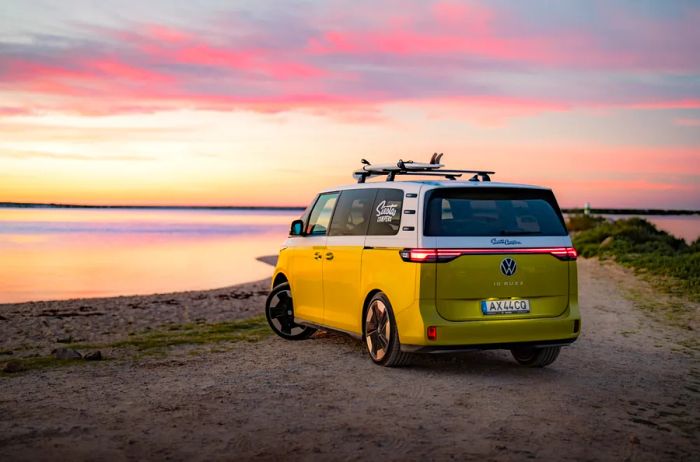 A yellow Volkswagen electric vehicle parked by a road near the water at sunset.