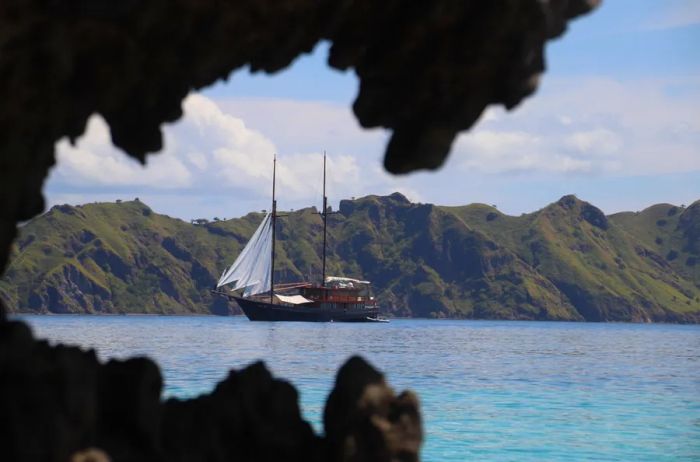 A sailing yacht set against the backdrop of an Indonesian island