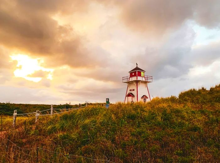 Red and white lighthouse on a grassy field