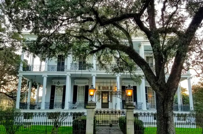 Facade of a two-story white plantation-style mansion in the Garden District, featuring grand columned porches