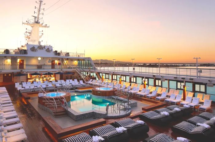 The pool deck of the Oceania Insignia cruise ship, featuring vacant loungers surrounding a cozy pool and hot tub.