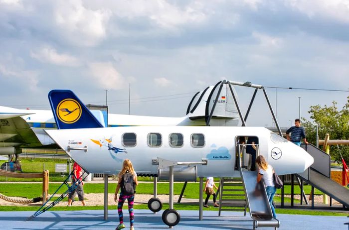 A children’s play area at Munich Airport, featuring a mock Lufthansa airplane and slide