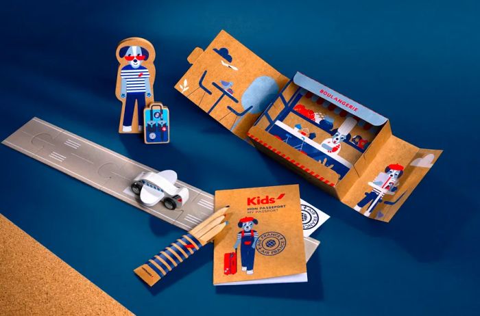 An Air France kids' amenity kit featuring coloring pencils, a booklet, and mini travel-themed cardboard cutouts of a dog wearing a beret