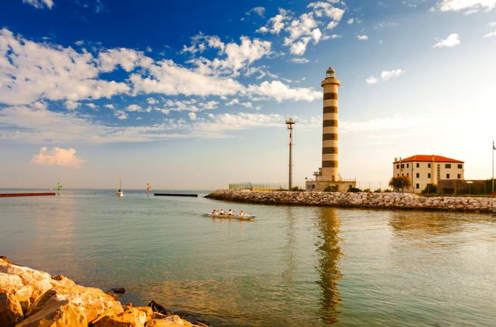 A lighthouse featuring bold horizontal red and white stripes, located on the beach at Lido di Jesolo, near Venice.