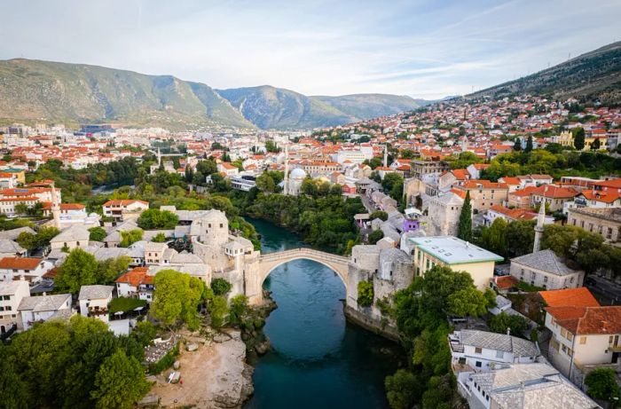 Stari Most bridge framed by red-roofed buildings and mountains