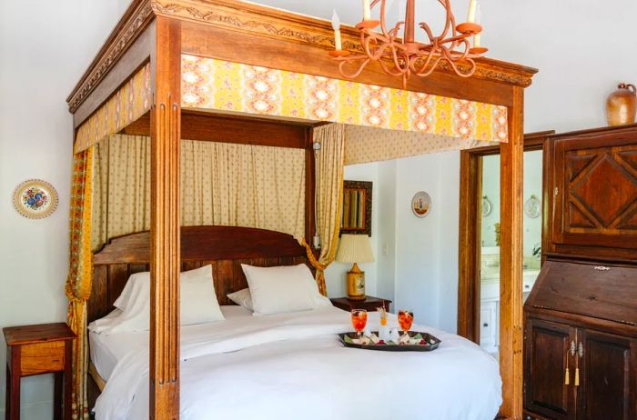 A guest room featuring a four-poster bed and a stunning chandelier