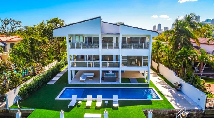 Rectangular pool beside a three-story white beach house 