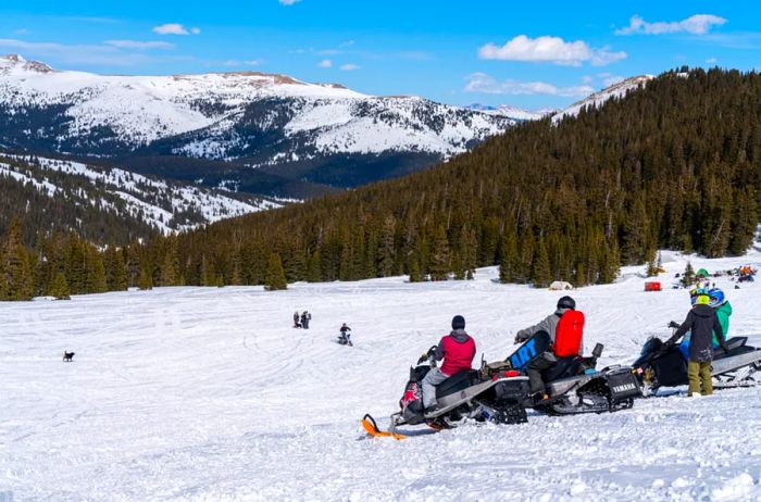 Three snowmobiles parked on a snowy mountain in Colorado