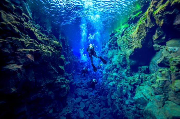 Four divers exploring an underwater canyon in Iceland.