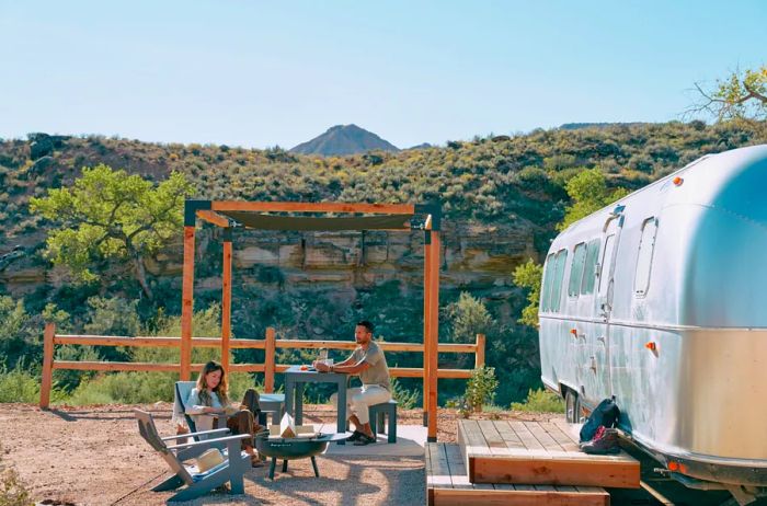 Guests enjoy the outdoors beside an Airstream.