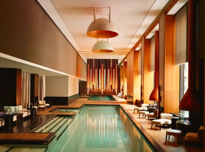 The 65-foot indoor pool at Aman New York is framed by daybeds and fireplaces.